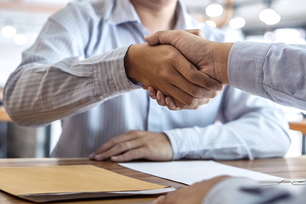 ABC Title Two men shaking hands at a desk. ABC Title Two men shaking hands at a desk.