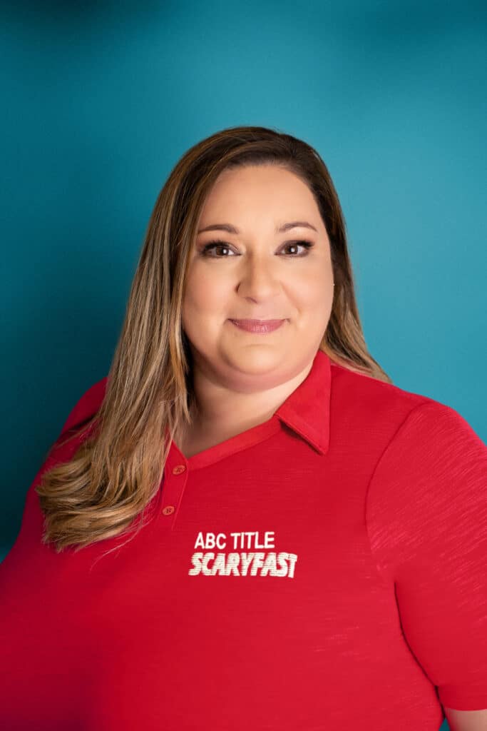 ABC Title A woman smiling, wearing a red shirt with the logo "ABC Title Scaryfast" against a teal background.